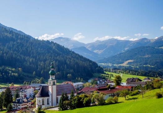 Landhotel Tirolerhof in Oberau Wildschönau mit Kirche und Bergpanorama im Sommer in Tirol