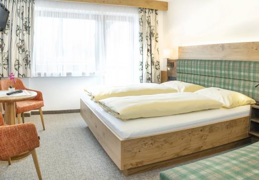 Komfortzimmer im Landhotel Tirolerhof in Oberau in der Wildschönau mit Doppelbett, Sitzecke und Balkon