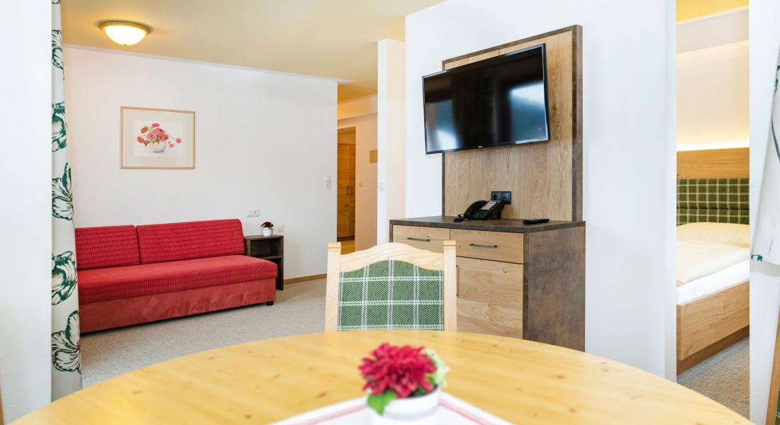 Living area in the apartment at the Landhotel Tirolerhof in Oberau in the Wildschönau with sofa, dining table and TV
