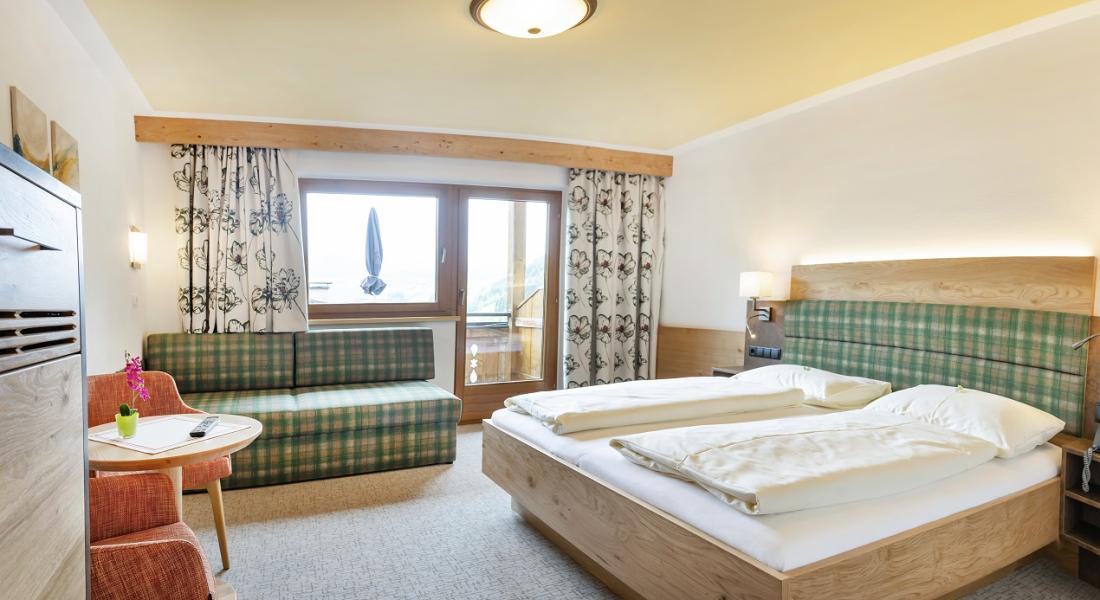 Comfortable room at the Landhotel Tirolerhof in Oberau in the Wildschönau with double bed, sofa and balcony