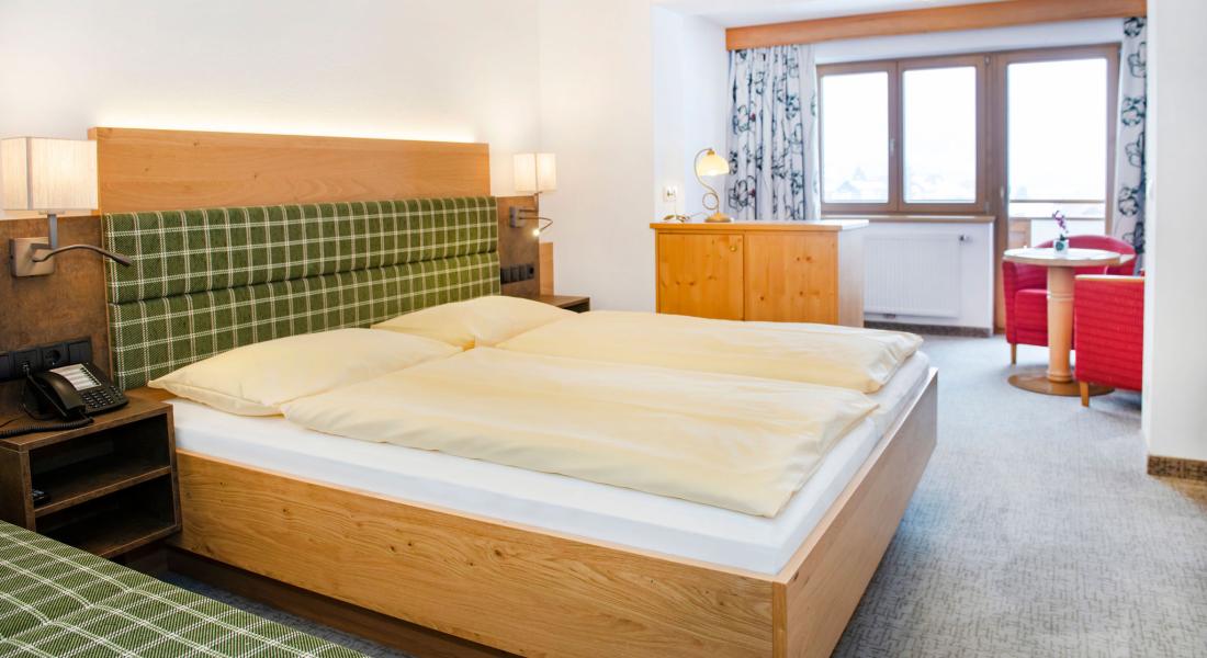 Komfortzimmer Deluxe Morgensonne mit Doppelbett und Sitzbereich im Landhotel Tirolerhof in der Wildschönau