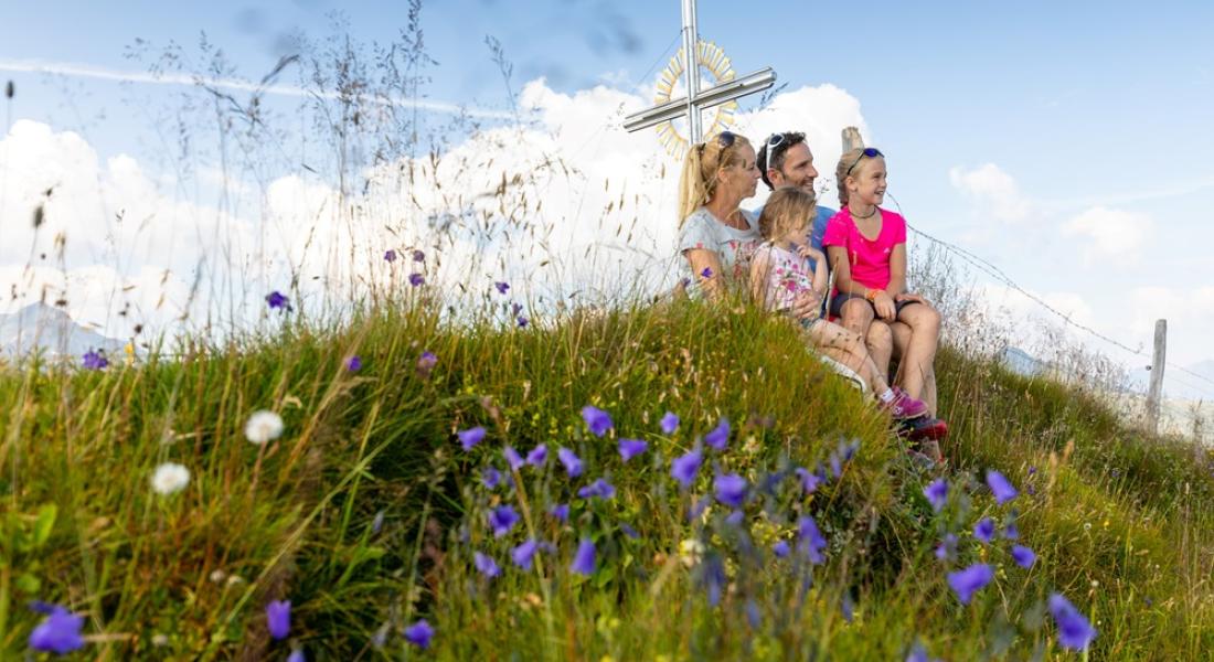 Familie mit Kindern beim Wandern auf einer Almwiese in der Wildschönau nahe Landhotel Tirolerhof Oberau mit Bergblick und Blumenwiese