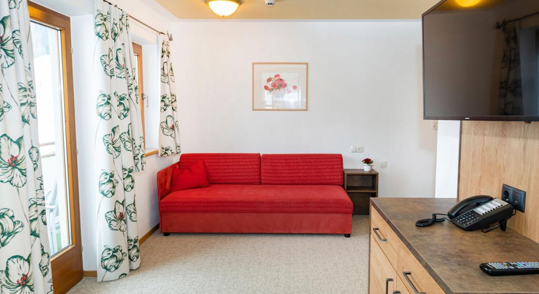 Living area in the apartment at the Landhotel Tirolerhof in Oberau in the Wildschönau with sofa and balcony access