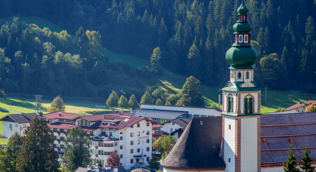 Landhotel Tirolerhof in Oberau in der Wildschönau mit Dorfkirche und Berglandschaft im Sommer